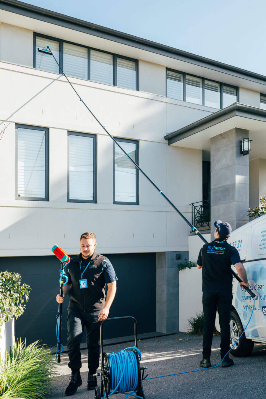 A MyHome window cleaning team cleaning external windows of a house with the UltraPure window cleaning system